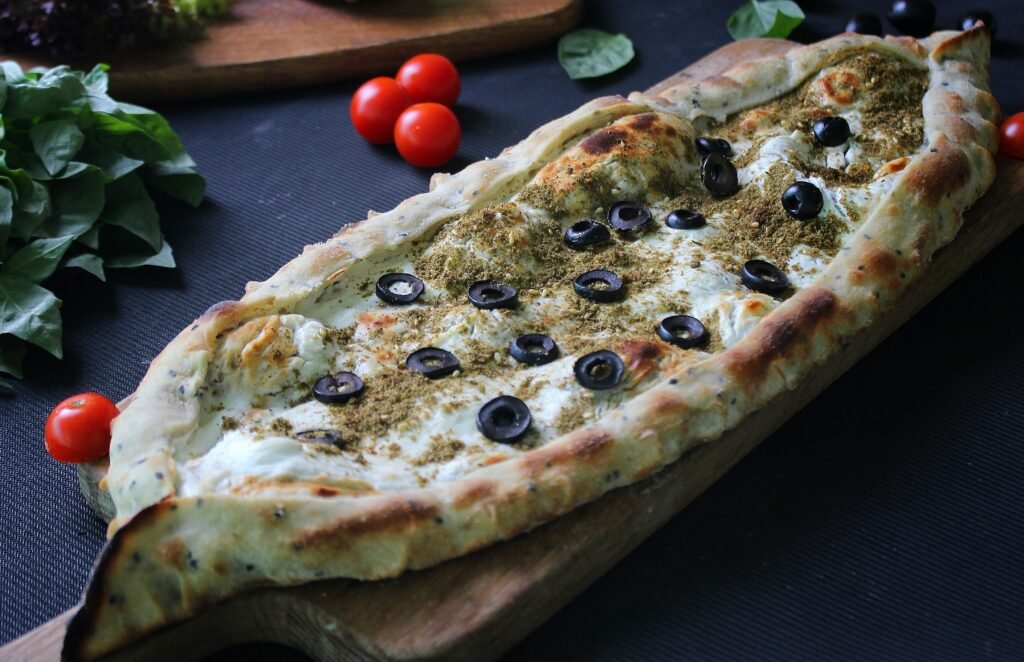 pexels-photo-5639253-5639253 Delicious Middle Eastern flatbread topped with herbs and olives on a wooden board.